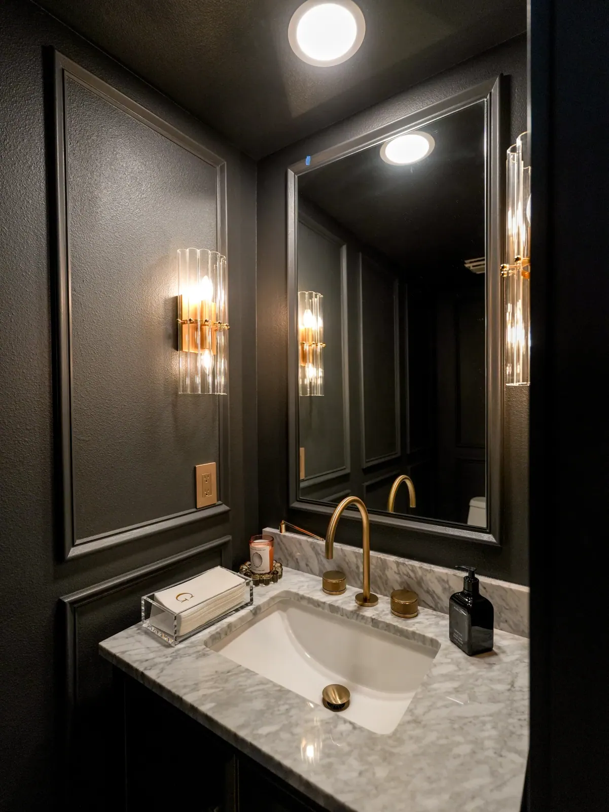 Black paneled powder room with a brass faucet